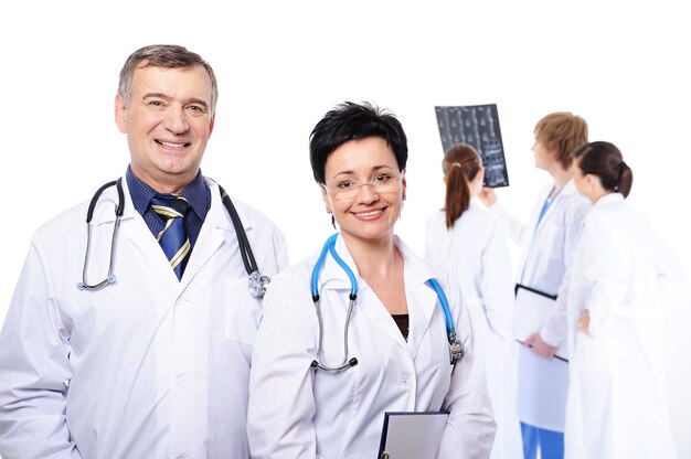 Happy laughing doctors at foreground and three doctors studying X-ray