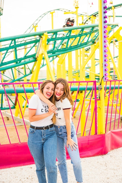 Happy lesbian couple standing in front of roller coaster ride