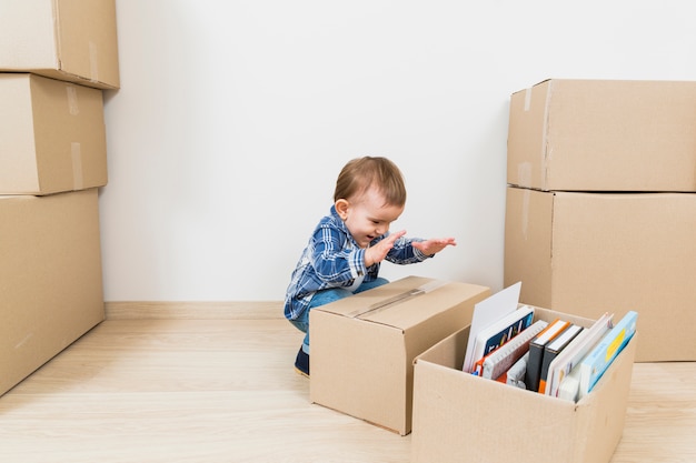 Счастливый маленький ребёнок играя с картонными коробками на новом доме