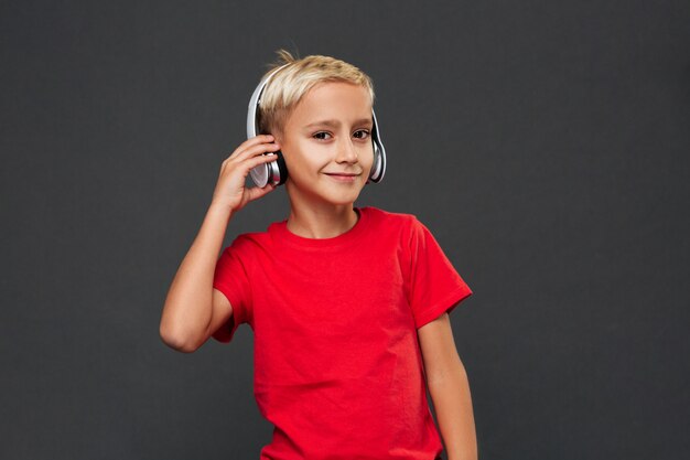 Happy little boy child listening music with headphones.