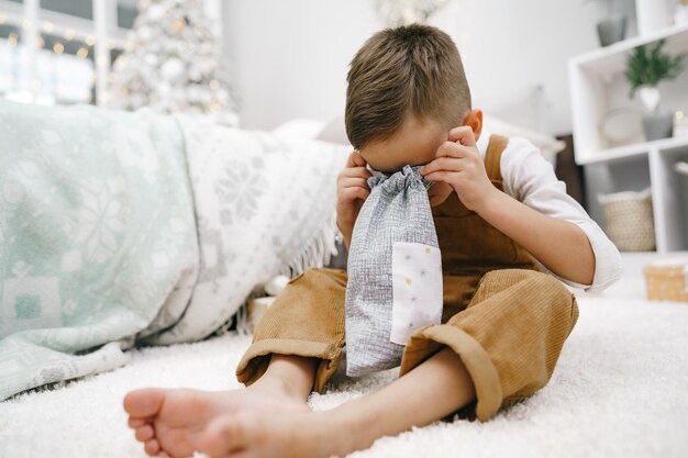 Happy little boy unwrapping his xmas gifts at home