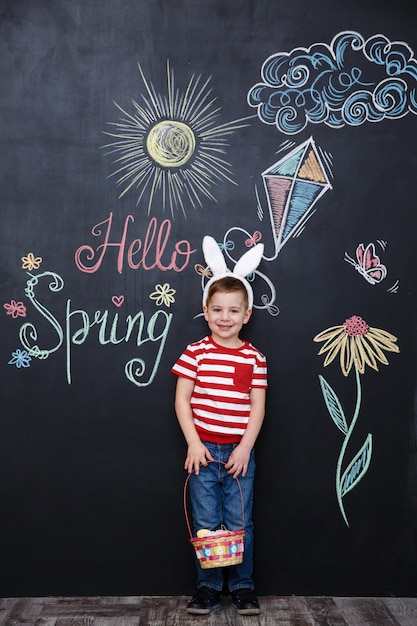 Free photo happy little boy wearing bunny ears and holding easter basket