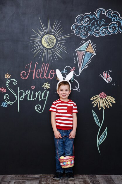 Happy little boy wearing bunny ears and holding easter basket