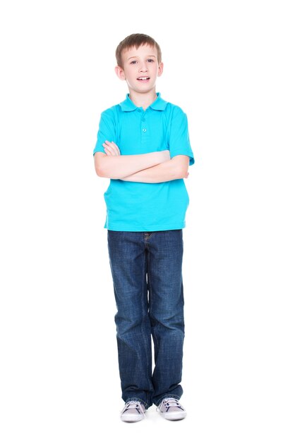 Happy little boy with crossed hands looking at camera in full length standing on white background.