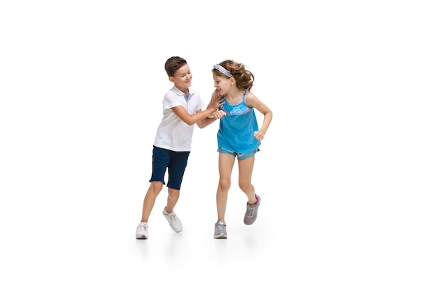Happy little caucasian girl and boy jumping and running isolated on white
