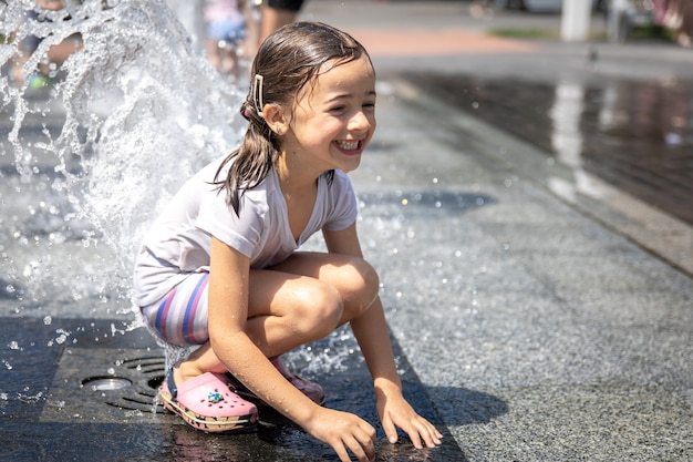 無料写真 街の噴水の水しぶきの中で幸せな少女。