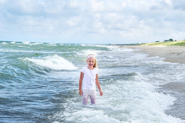 Happy little girl in clothes on the baltic sea beach on the curonian spit in lithuania.