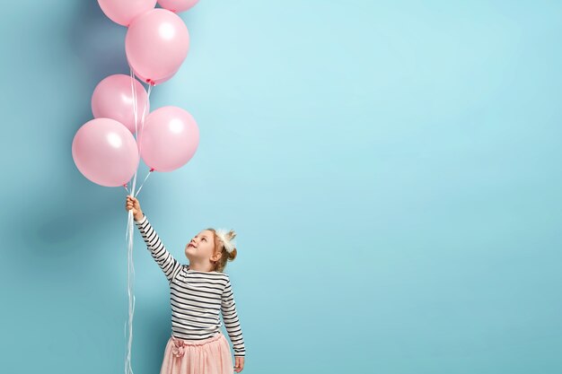 Happy little girl holding balloons