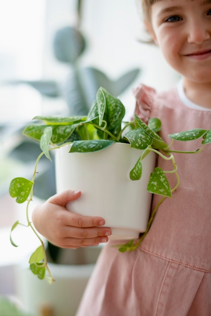Bambina felice a casa con piante d'appartamento