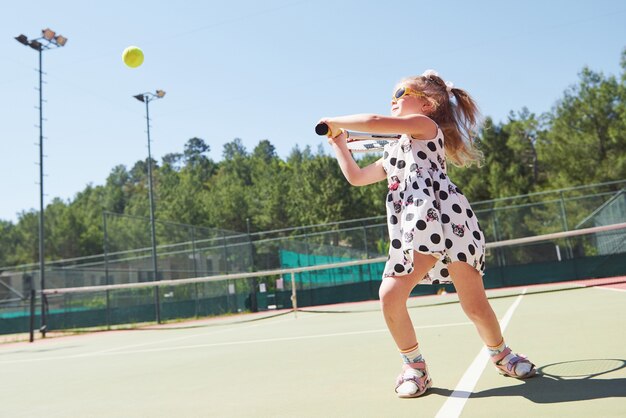 Happy little girl playing tennis. Summer sport