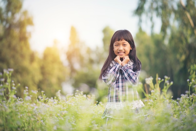 Bambina felice che si leva in piedi nel prato