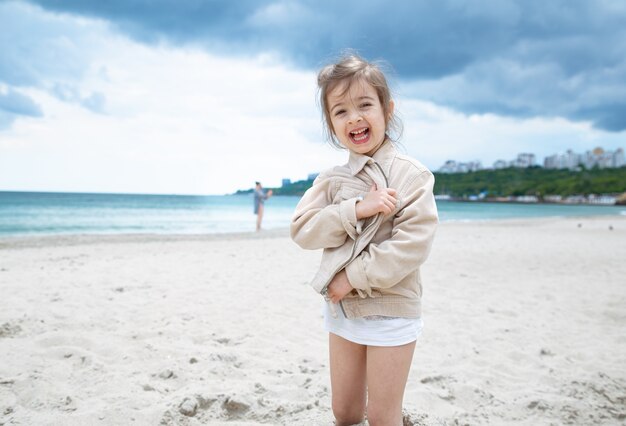 Happy little girl on a sunny day on the beach by the sea.