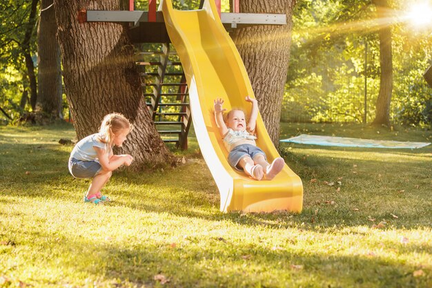 Happy little girls rolling down the hill on the playground