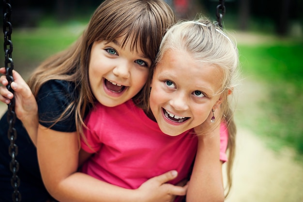 Bambine felici che oscillano in un parco