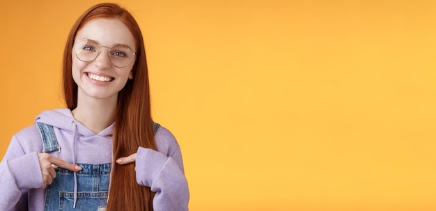 Happy lively friendly redhead european girl pointing herself suggesting help boasting telling own