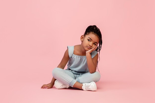 ピンクのスタジオの背景に分離された幸せな長髪ブルネットの少女幸せで陽気な誠実なコピースペース幼児教育感情の概念に見えます