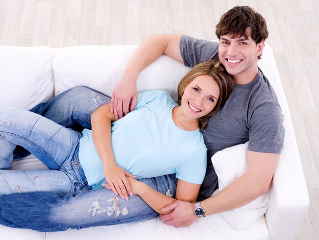 Счастливая влюбленная пара, лежа на диване в повседневной одежде - высокий угол