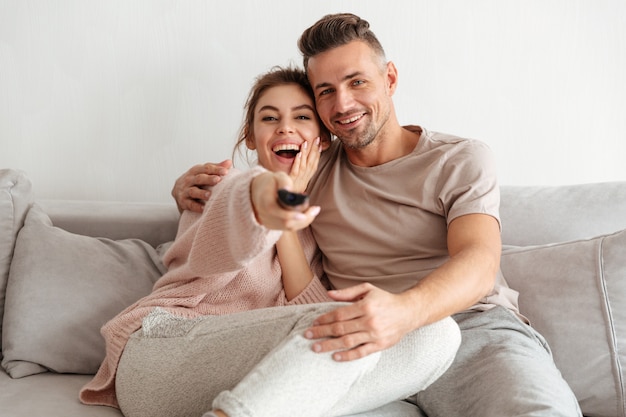 Happy loving couple sitting on couch together and watching TV