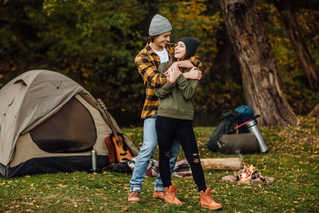 텐트 근처 숲에서 캐주얼 옷을 입은 행복한 사랑하는 커플