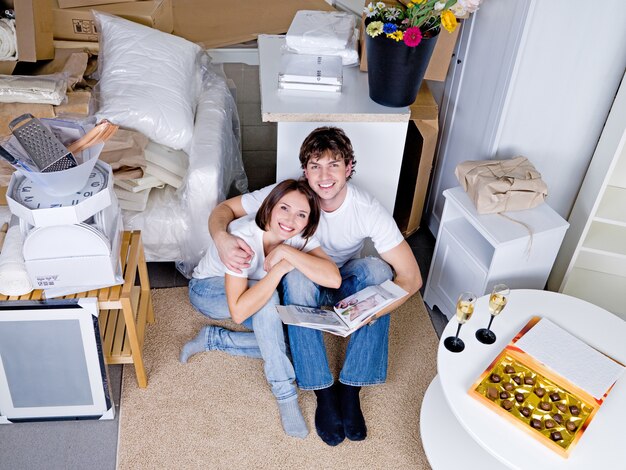 Happy loving smiling couple sitting on the floor with photo album