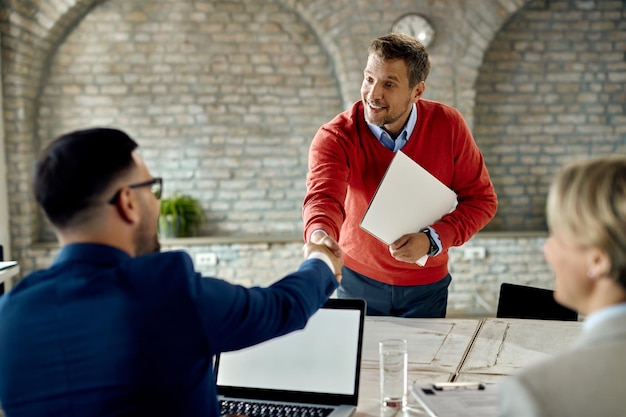 Free photo happy male candidate shaking hands with members of human resource team on a job interview in the office