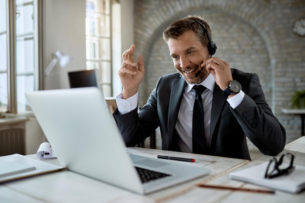 Free photo happy male entrepreneur having a video call over laptop while working in the office