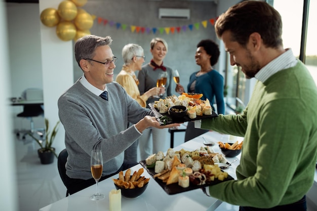 Foto gratuita imprenditori maschi felici che apparecchiano la tavola per la festa in ufficio