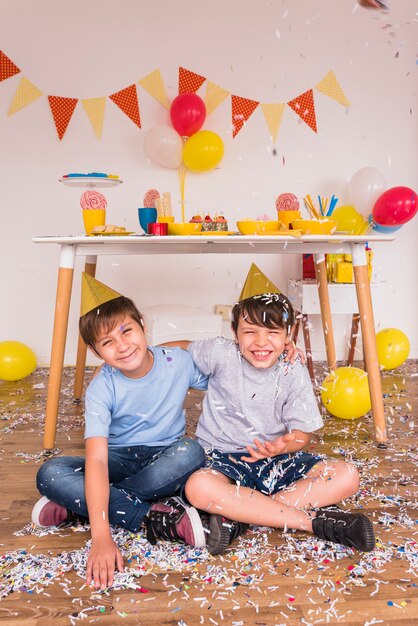 Amici maschii felici che giocano con i coriandoli durante la celebrazione di compleanno