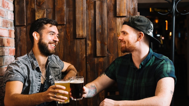 Счастливые друзья-мужчины, жарящие стакан алкогольных напитков