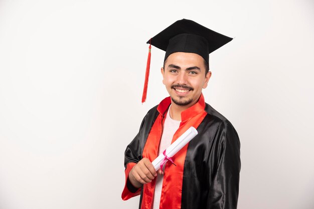 Happy male student with diploma standing on white.