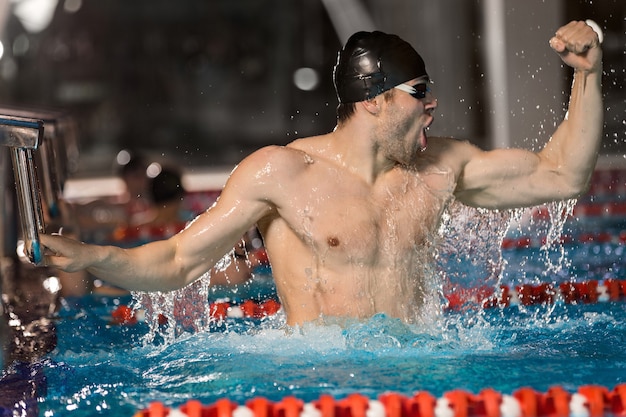 Free photo happy male swimmer holding starting block