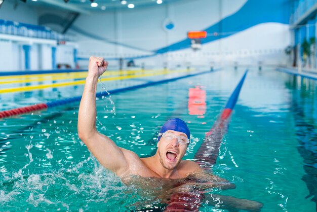 Счастливый мужской пловец поднимая руку в воде