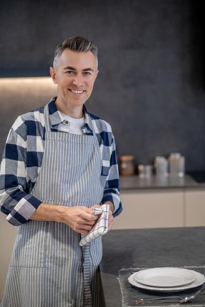 Happy man in apron with napkin looking at camera