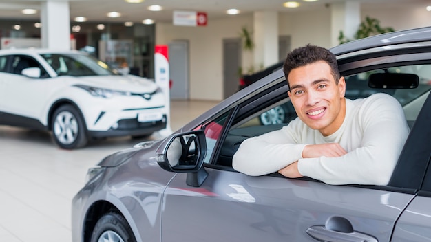 Happy man in car dealership