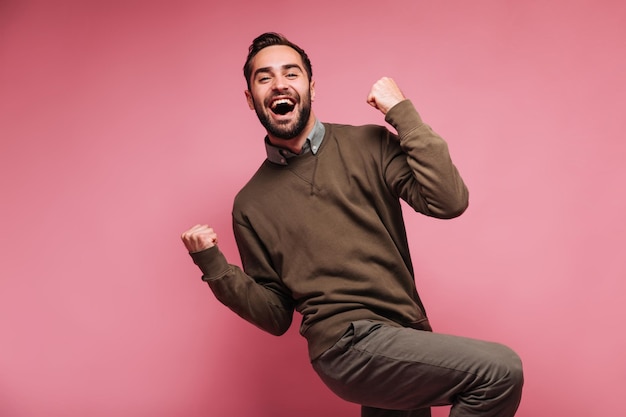 Happy man celebrates victory and smiles on pink background