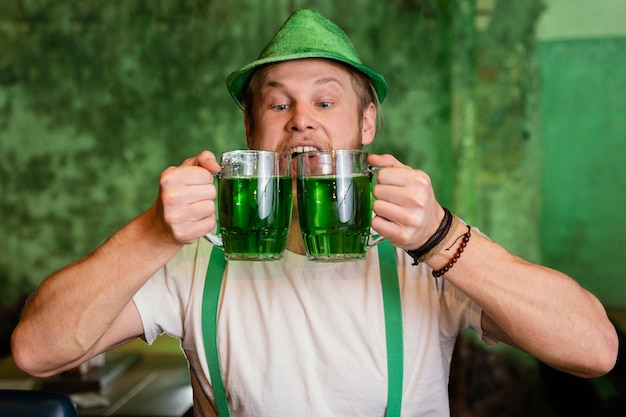 Foto gratuita uomo felice che celebra st. patrick's day al bar con bevande