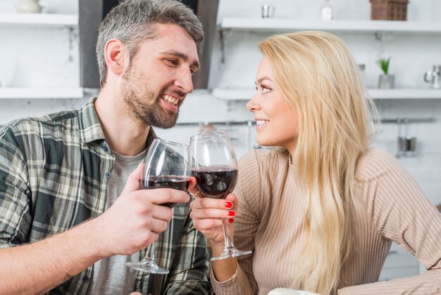 Happy man clanging glasses with cheerful woman in kitchen