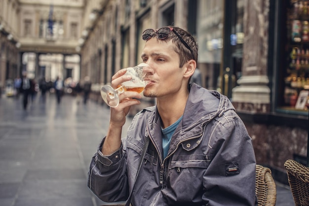 Happy man drinking bear on the street.