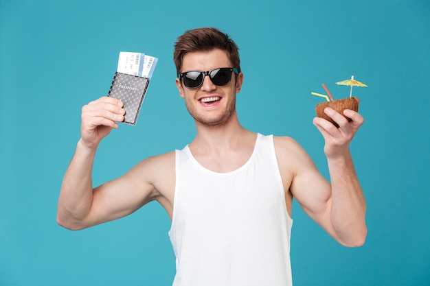 Happy man drinking cocktail holding tickets.