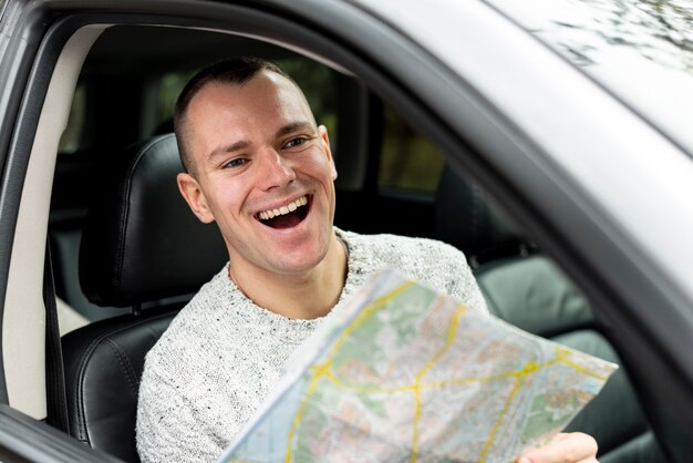 Happy man driving and holding a map