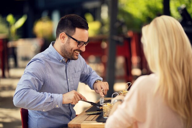 レストランでガールフレンドと食事をしながら楽しんで幸せな男