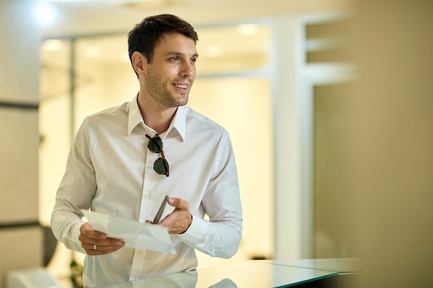 Happy man filling hotel reservation form while registering at reception desk