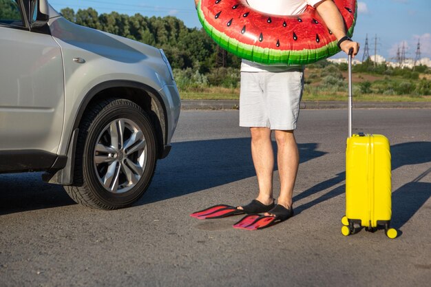 Happy man in flippers inflatable ring with bag going to car sea vacation concept