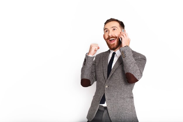 Счастливый человек в сером костюме разговаривает по телефону