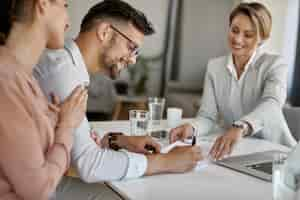 Free photo happy man and his wife having a meeting with financial advisor and signing an agreement in the office