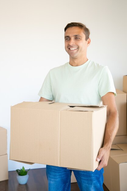 Happy man holding cardboard box in his new apartment or house