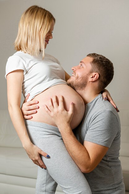 Happy man hugging pregnant woman at home