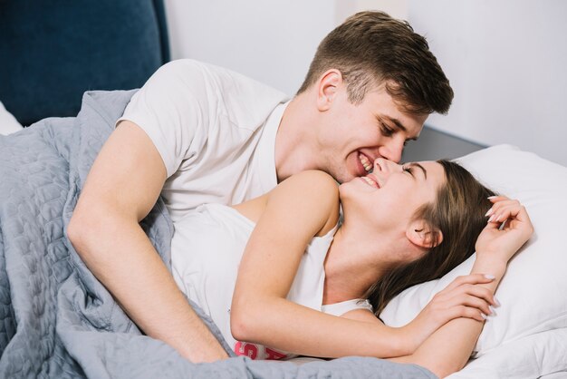 Happy man hugging woman in bed 