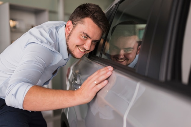 彼の新しい車を検査する幸せな男