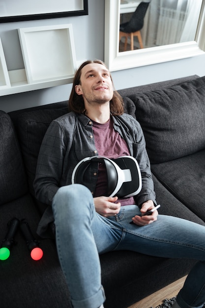 Foto gratuita l'uomo felice si trova sul sofà a casa che tiene i vetri 3d